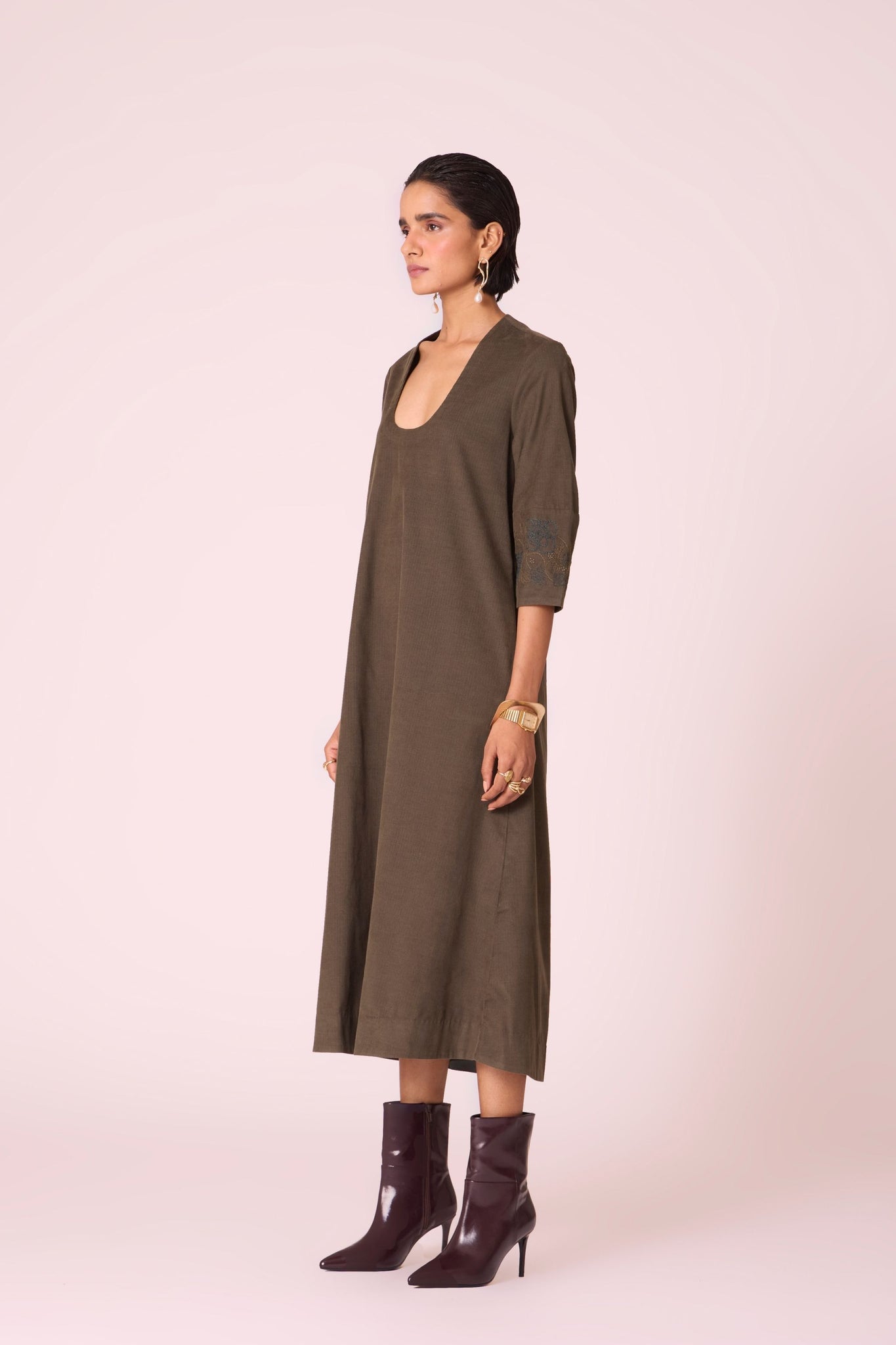Olive needlecord A-line dress with drop shoulder, hand-embroidered cuff, deep scoop neckline, and in-seam pockets.