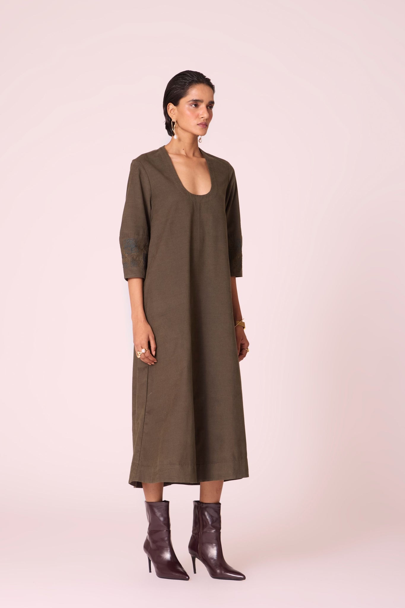Olive needlecord A-line dress with drop shoulder, hand-embroidered cuff, deep scoop neckline, and in-seam pockets.