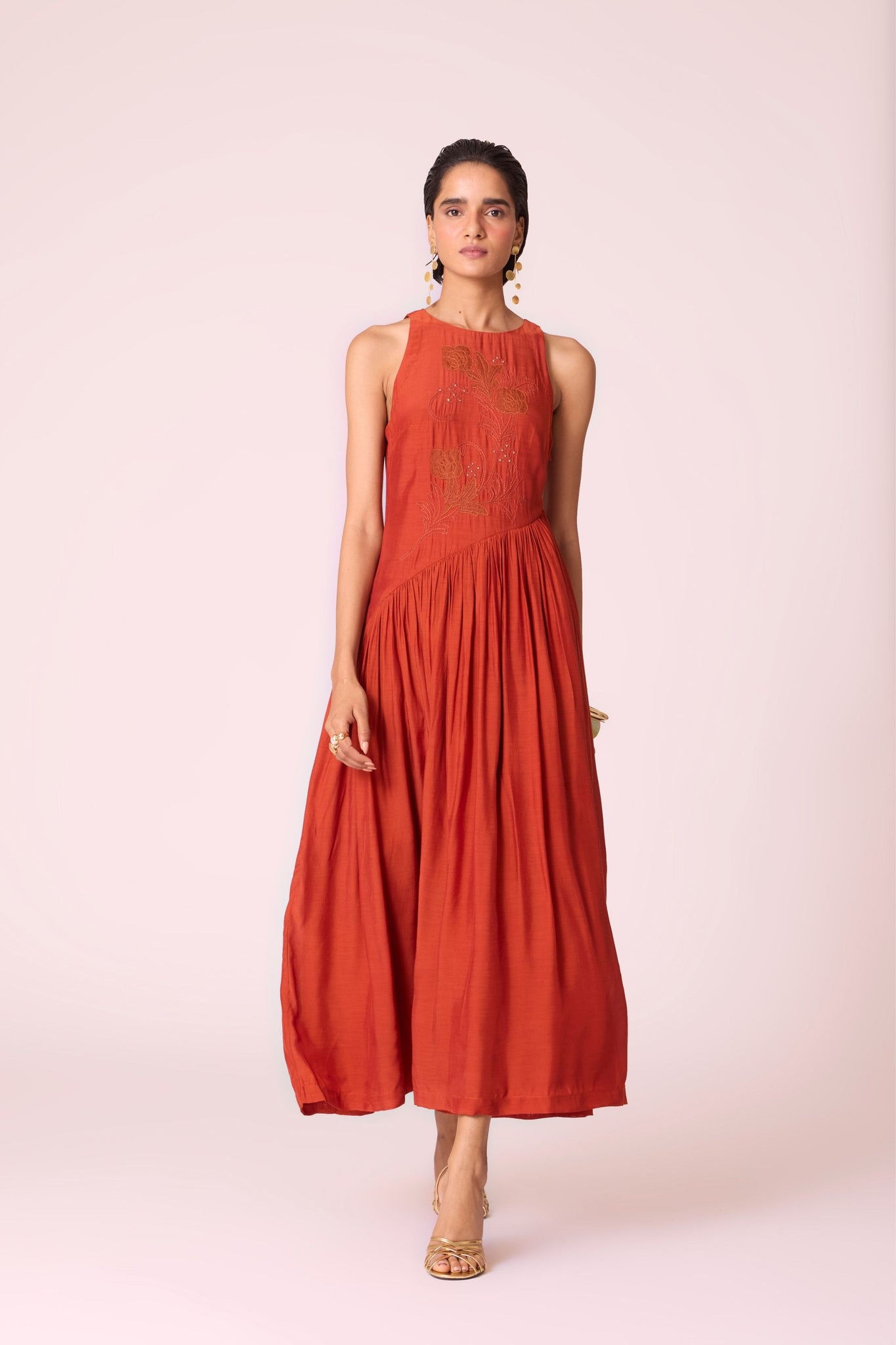 Rust cupro midi dress with hand-embroidered bodice, asymmetric gathered waist, and rouleau back button.

