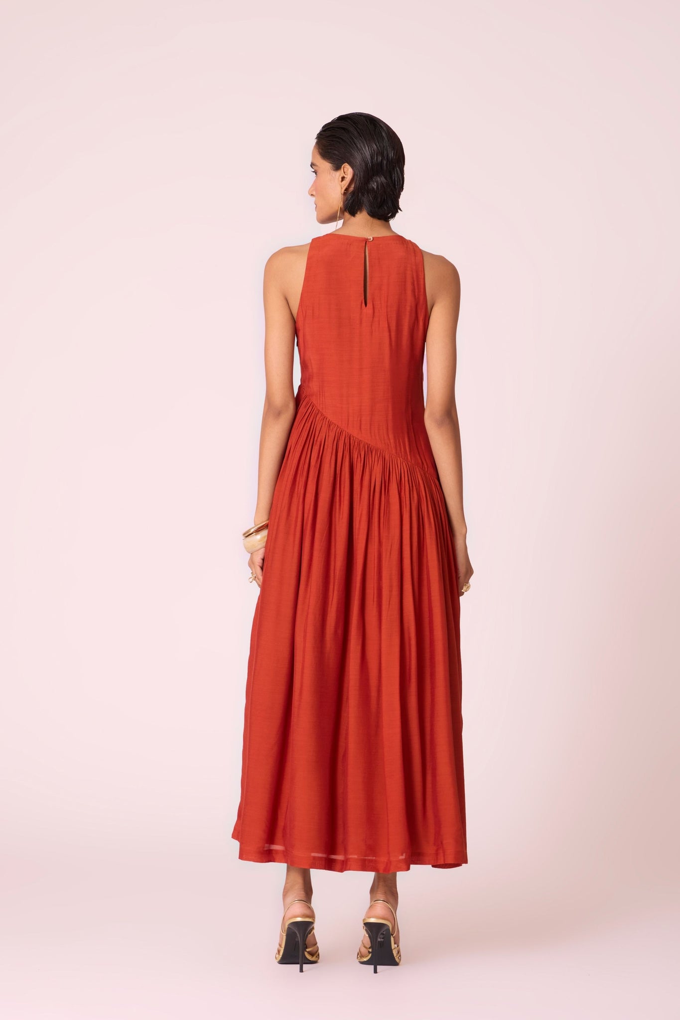 Rust cupro midi dress with hand-embroidered bodice, asymmetric gathered waist, and rouleau back button.
