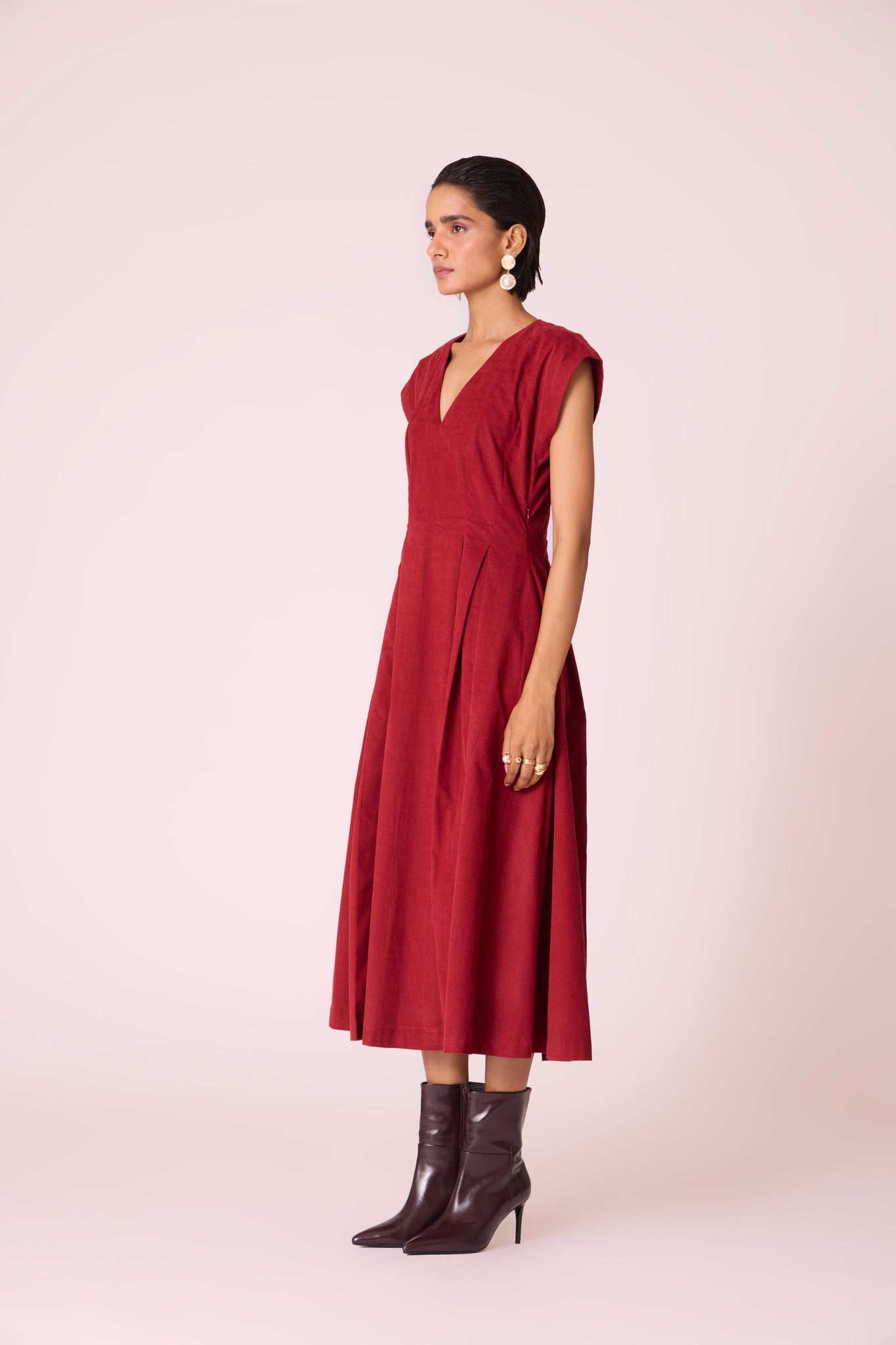 Rust needlecord panelled dress with box pleats, structured drop shoulder, V-neckline, side zip, and in-seam pockets.