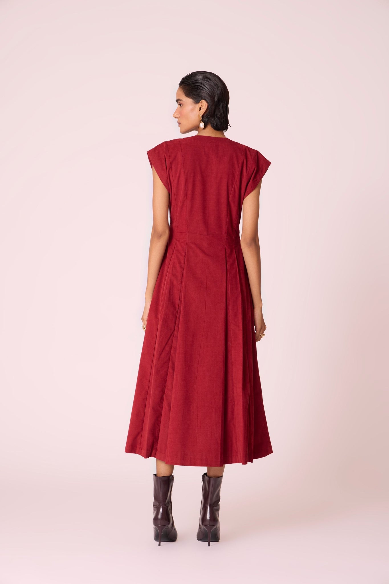 Rust needlecord panelled dress with box pleats, structured drop shoulder, V-neckline, side zip, and in-seam pockets.