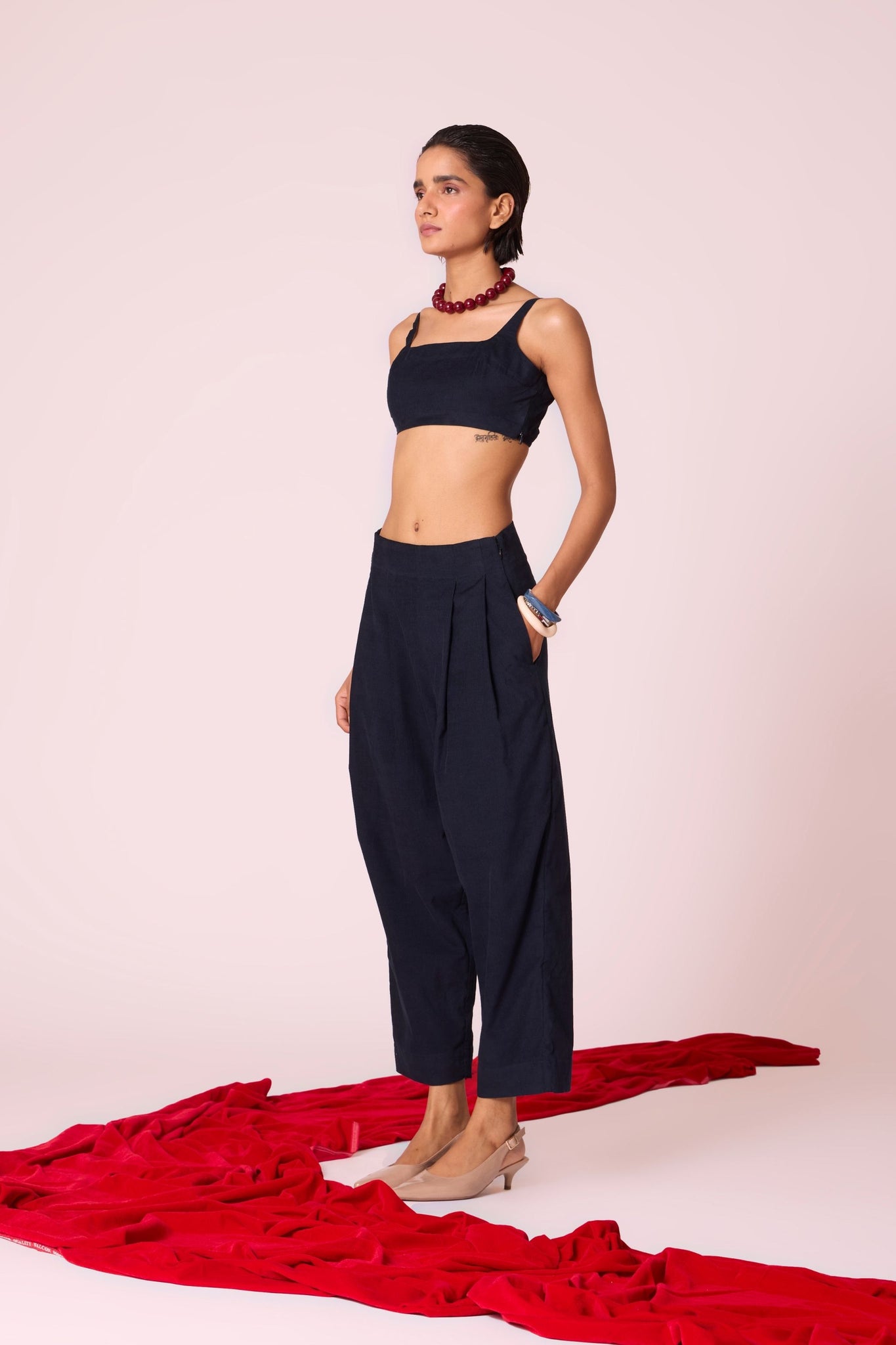 Navy needlecord high-rise cropped pants with four front pleats, side zip, and in-seam pockets.
