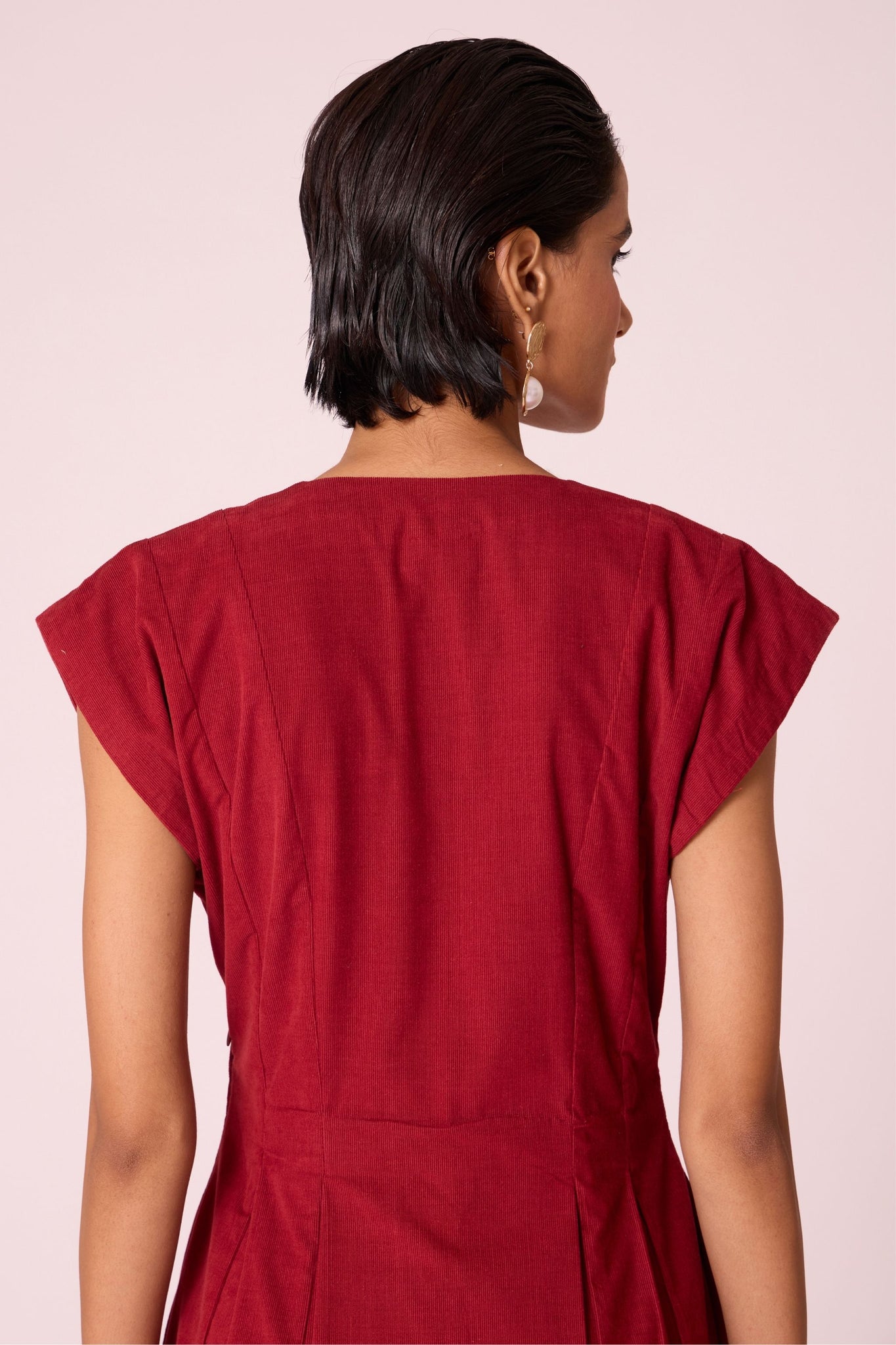 Rust needlecord panelled dress with box pleats, structured drop shoulder, V-neckline, side zip, and in-seam pockets.