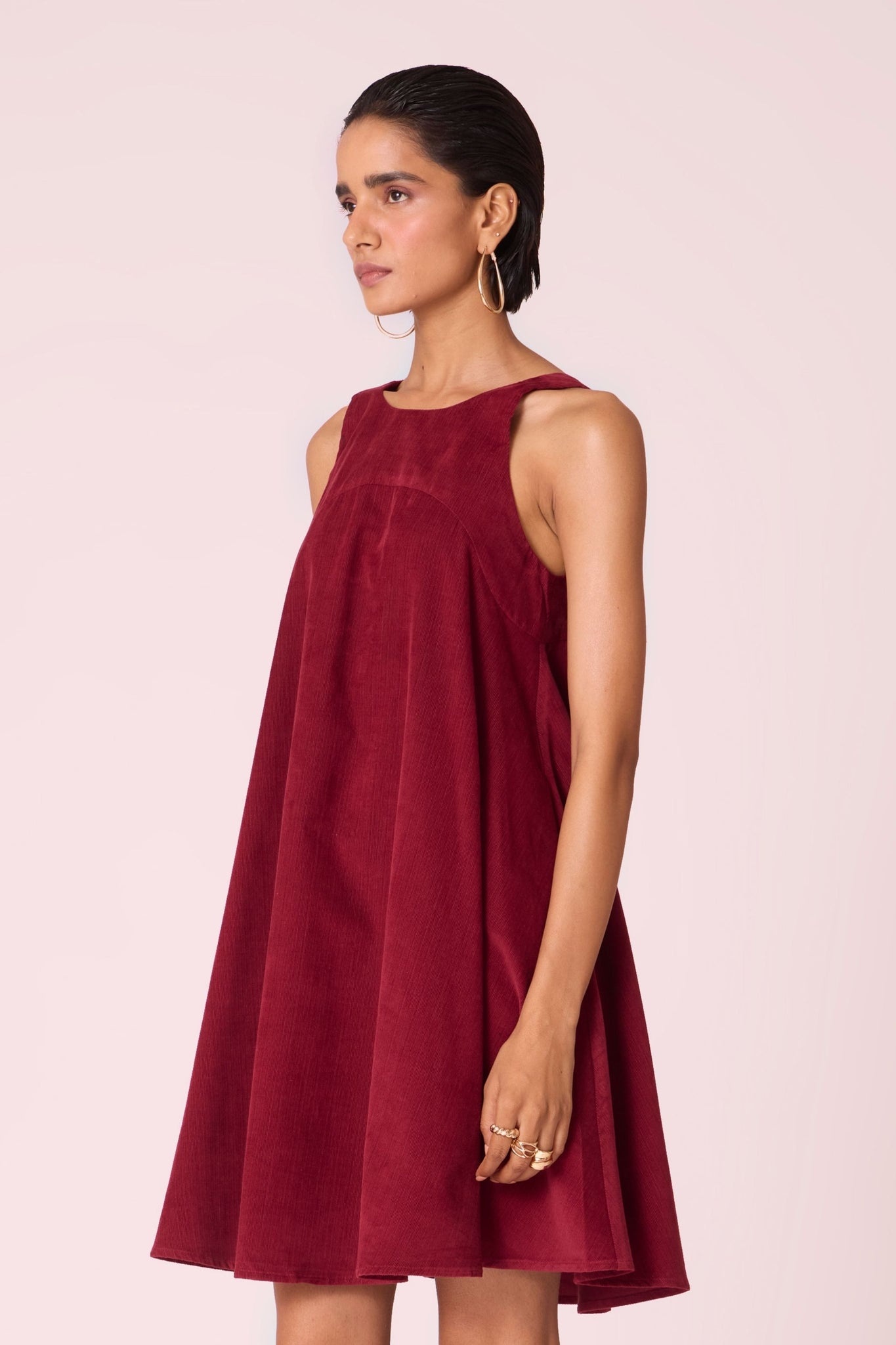Cherry needlecord tent dress with incut shoulder, low scoop back, and in-seam pockets.
