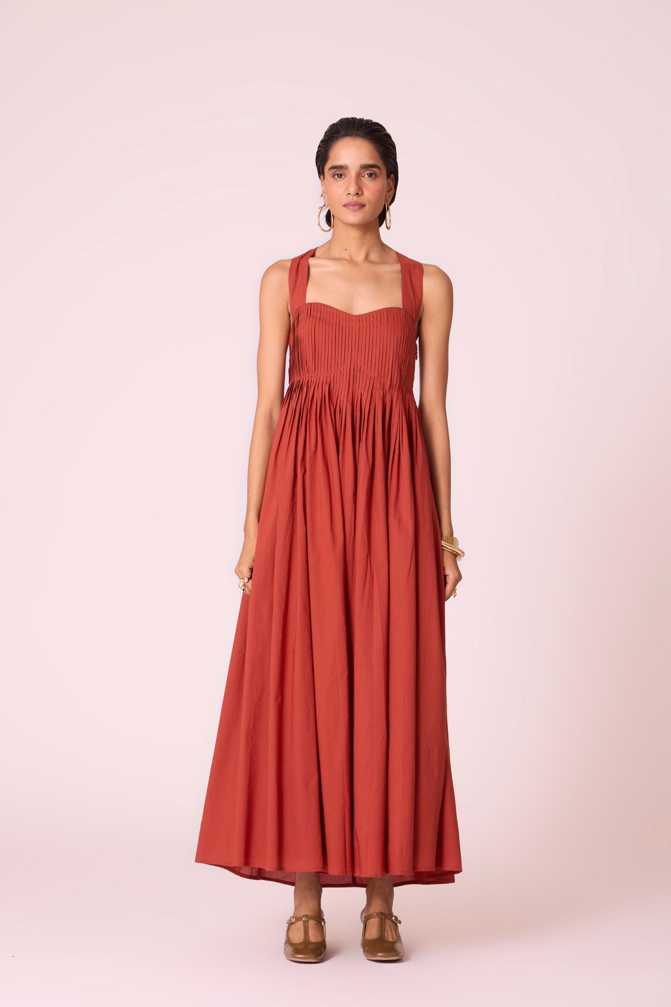 Rust pleated dress in organic cotton voile with a square neckline, thick straps, and a fully lined flared silhouette.
