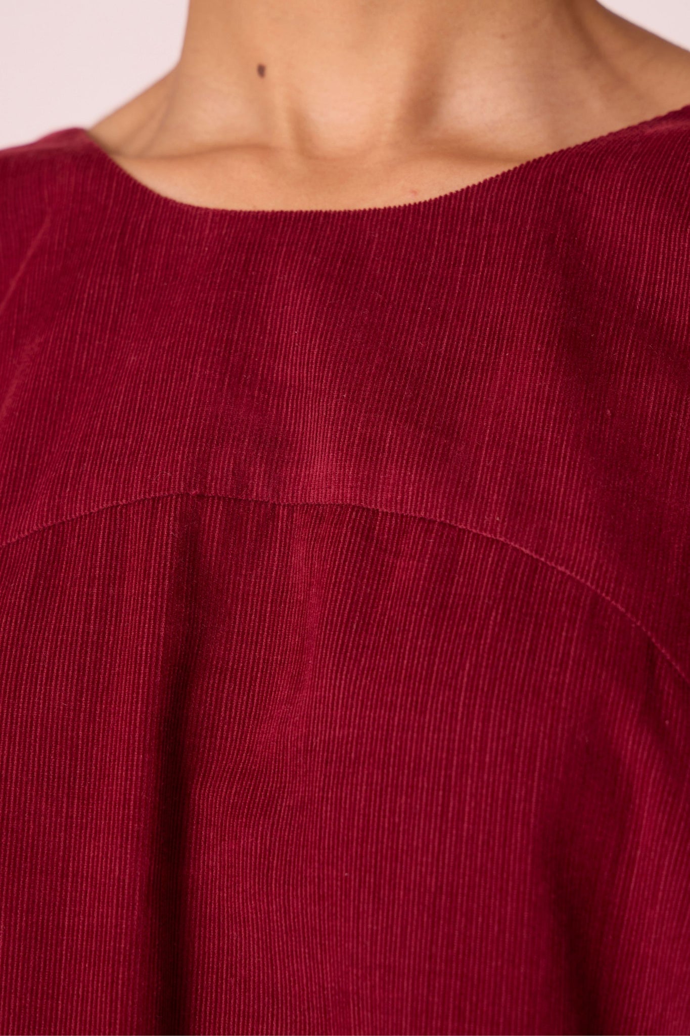 Cherry needlecord tent dress with incut shoulder, low scoop back, and in-seam pockets.
