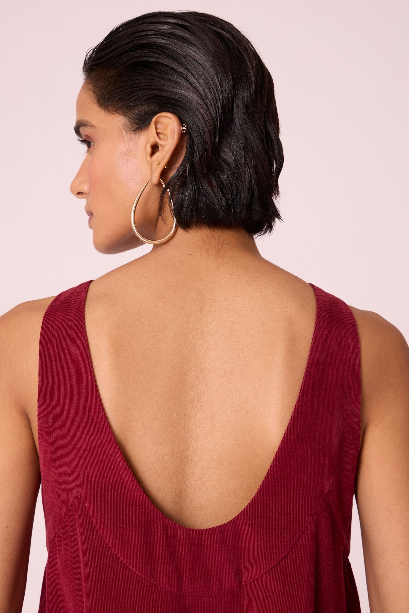 Cherry needlecord tent dress with incut shoulder, low scoop back, and in-seam pockets.
