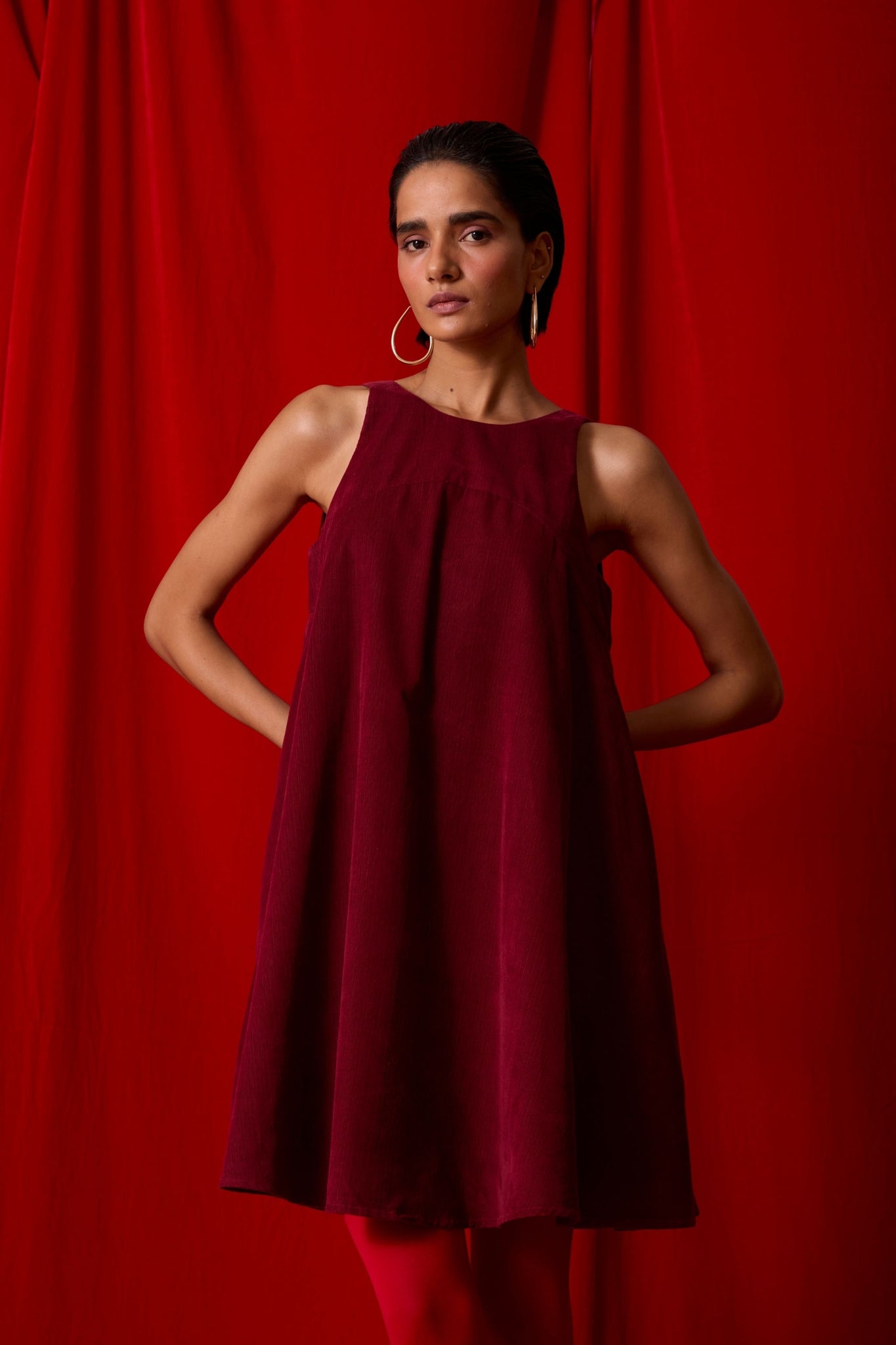 Cherry needlecord tent dress with incut shoulder, low scoop back, and in-seam pockets.
