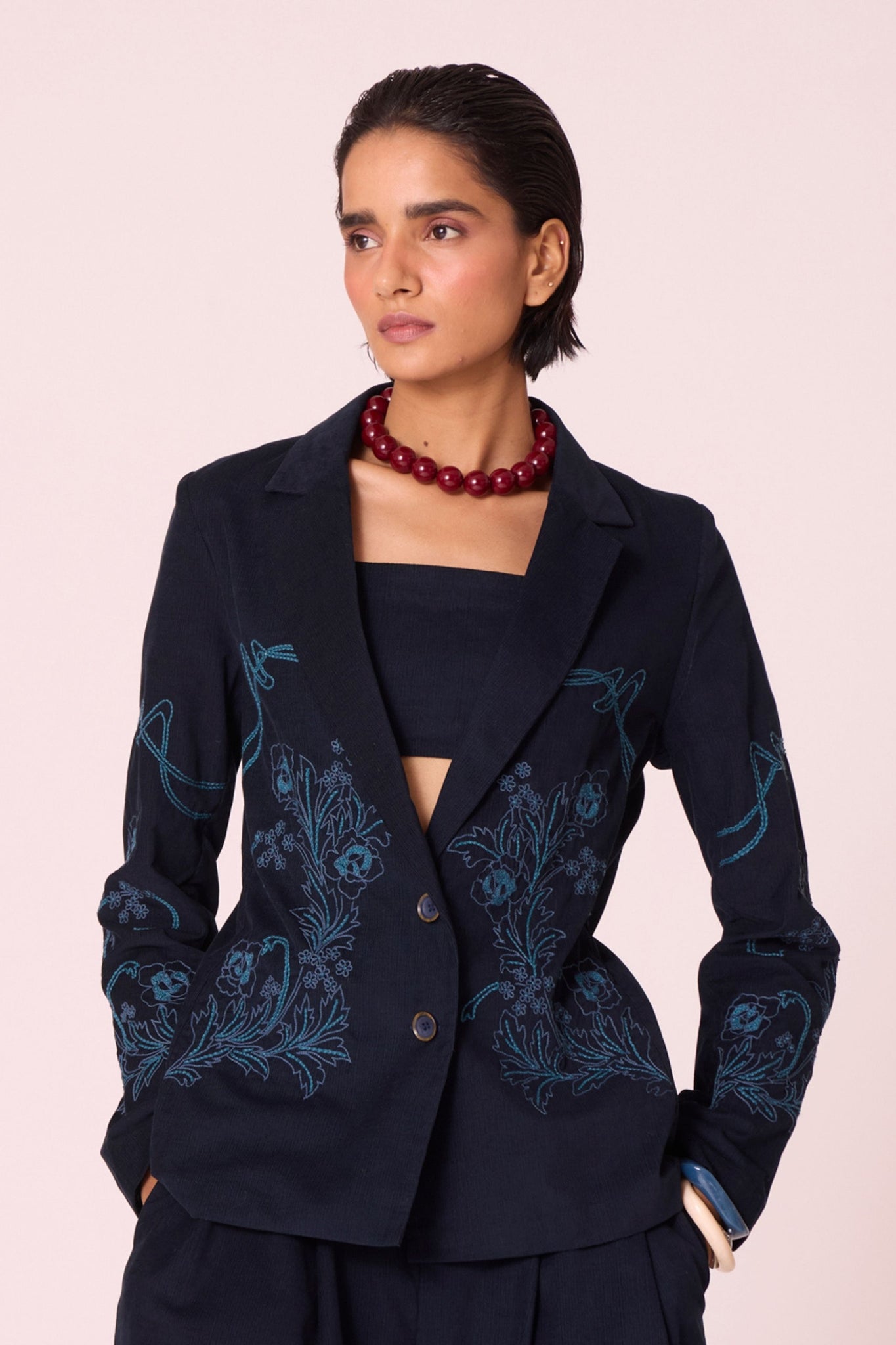 Navy needlecord slim-fit jacket with hand-embroidered waist and sleeves, notch collar, and full-length sleeves.
