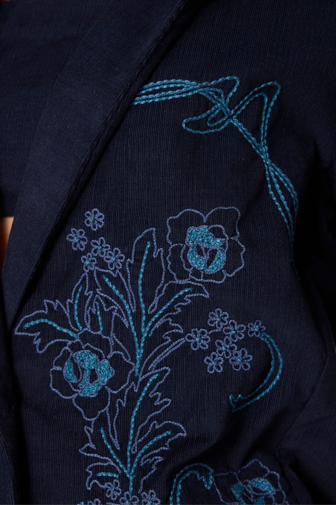 Navy needlecord slim-fit jacket with hand-embroidered waist and sleeves, notch collar, and full-length sleeves.
