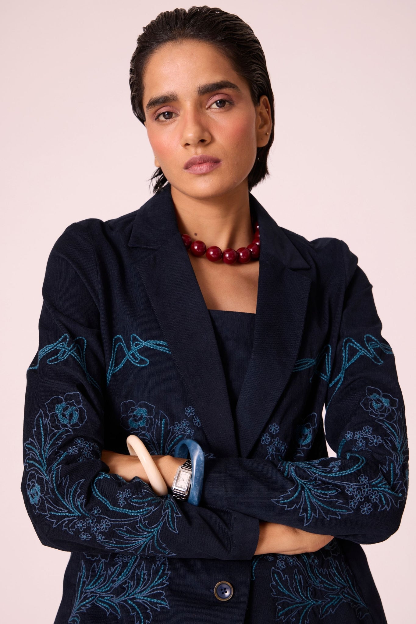 Navy needlecord slim-fit jacket with hand-embroidered waist and sleeves, notch collar, and full-length sleeves.
