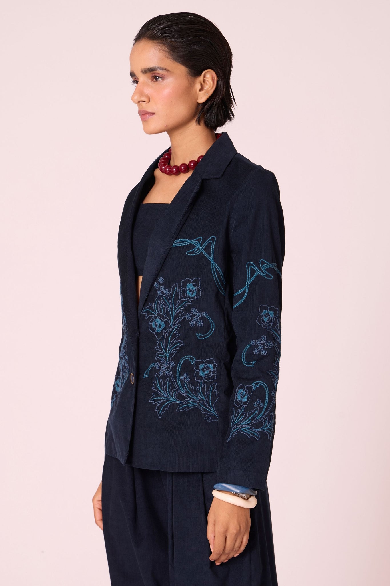 Navy needlecord slim-fit jacket with hand-embroidered waist and sleeves, notch collar, and full-length sleeves.
