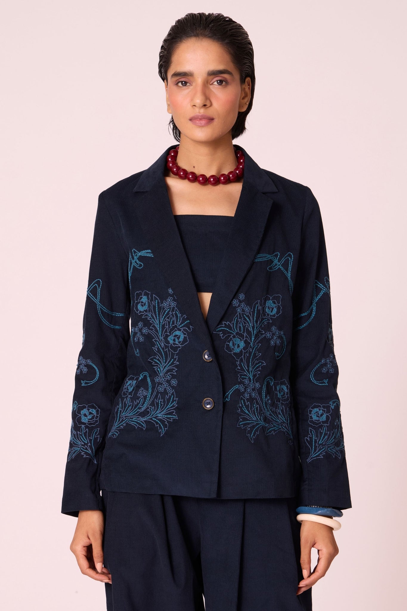 Navy needlecord slim-fit jacket with hand-embroidered waist and sleeves, notch collar, and full-length sleeves.
