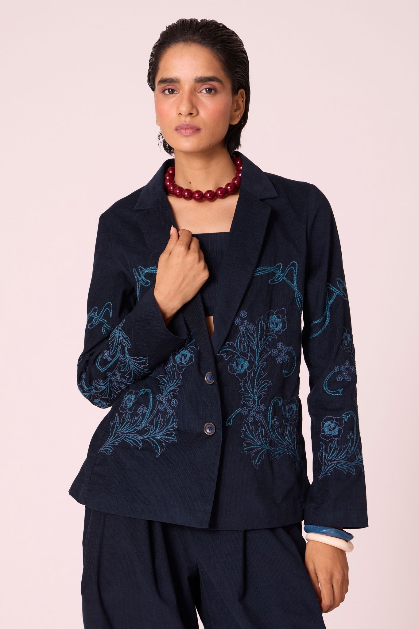 Navy needlecord slim-fit jacket with hand-embroidered waist and sleeves, notch collar, and full-length sleeves.
