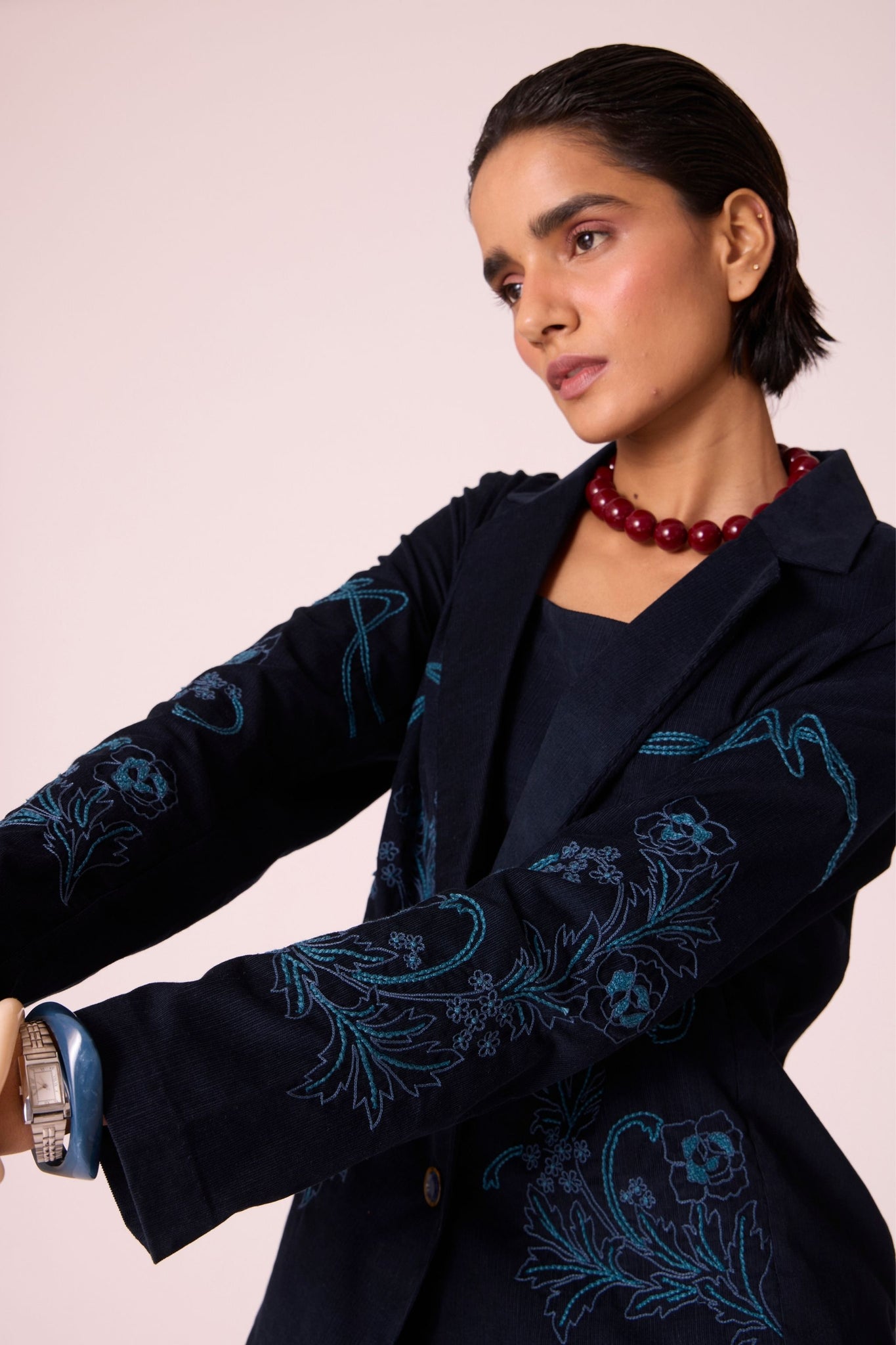 Navy needlecord slim-fit jacket with hand-embroidered waist and sleeves, notch collar, and full-length sleeves.
