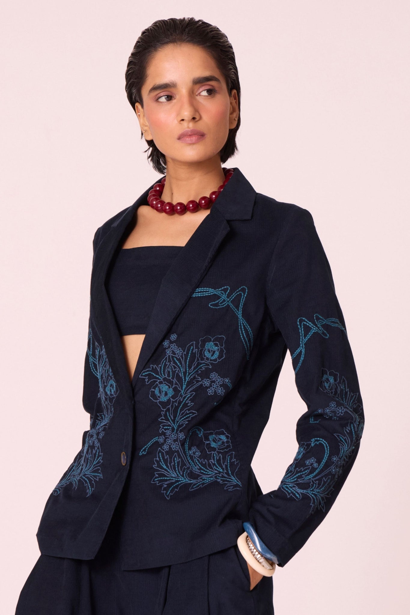 Navy needlecord slim-fit jacket with hand-embroidered waist and sleeves, notch collar, and full-length sleeves.
