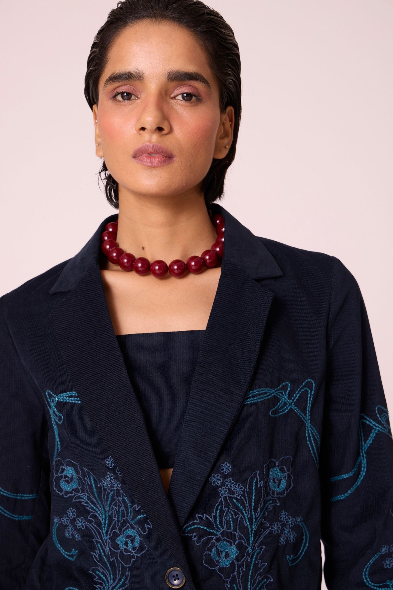 Navy needlecord slim-fit jacket with hand-embroidered waist and sleeves, notch collar, and full-length sleeves.

