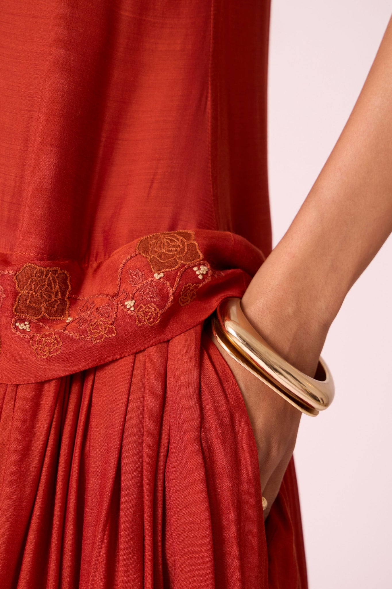 Rust cupro drop-waist dress with hand-embroidered waist, narrow scooped neckline, and full lining.
