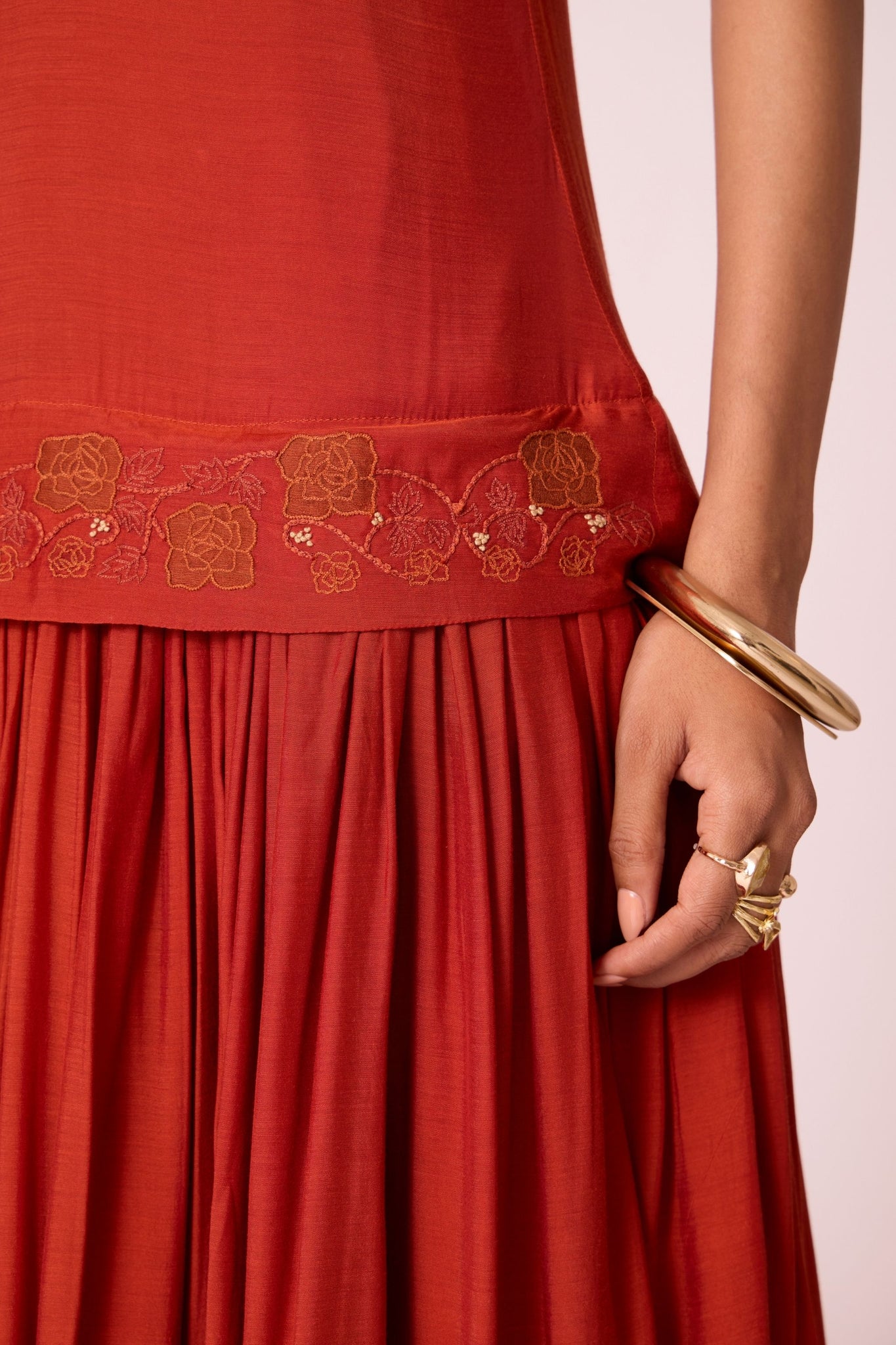 Rust cupro drop-waist dress with hand-embroidered waist, narrow scooped neckline, and full lining.

