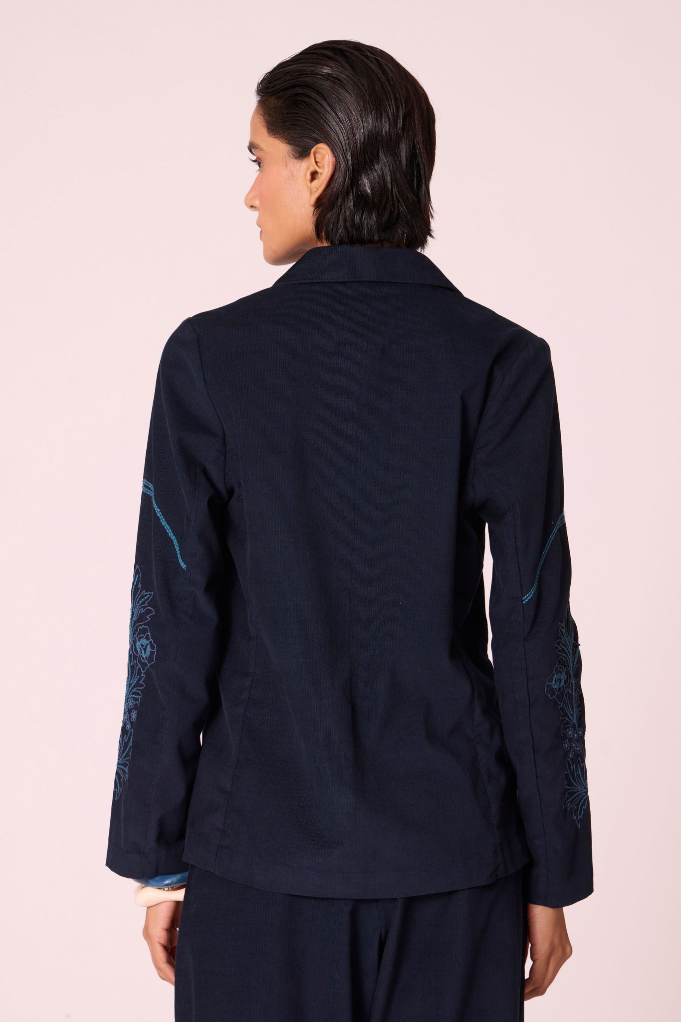 Navy needlecord slim-fit jacket with hand-embroidered waist and sleeves, notch collar, and full-length sleeves.
