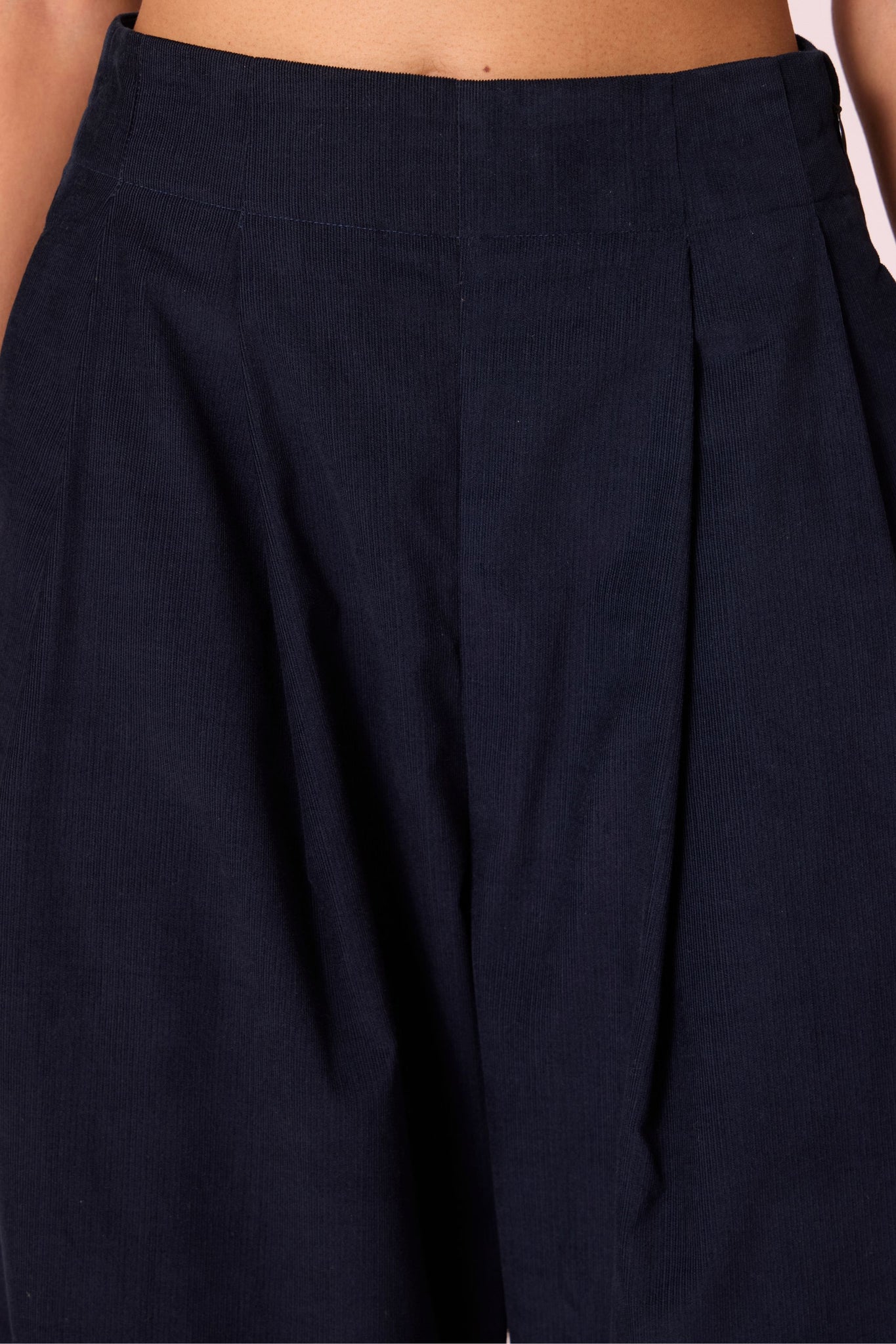Navy needlecord high-rise cropped pants with four front pleats, side zip, and in-seam pockets.

