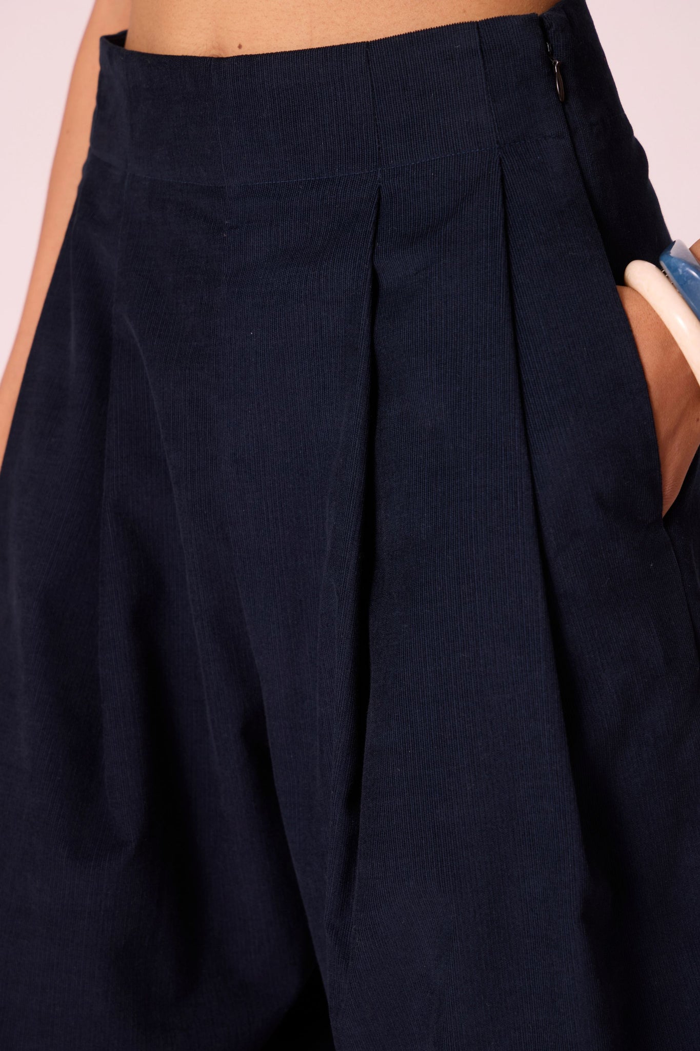 Navy needlecord high-rise cropped pants with four front pleats, side zip, and in-seam pockets.
